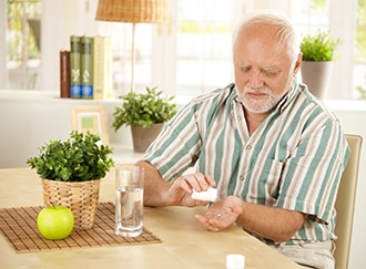 Un hombre sentado tomando una medicina oral con agua.