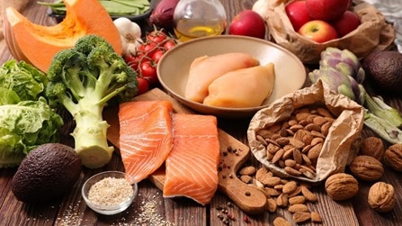  A table displaying a variety of healthy foods, such as squash, almonds, apples, salmon, and rice.