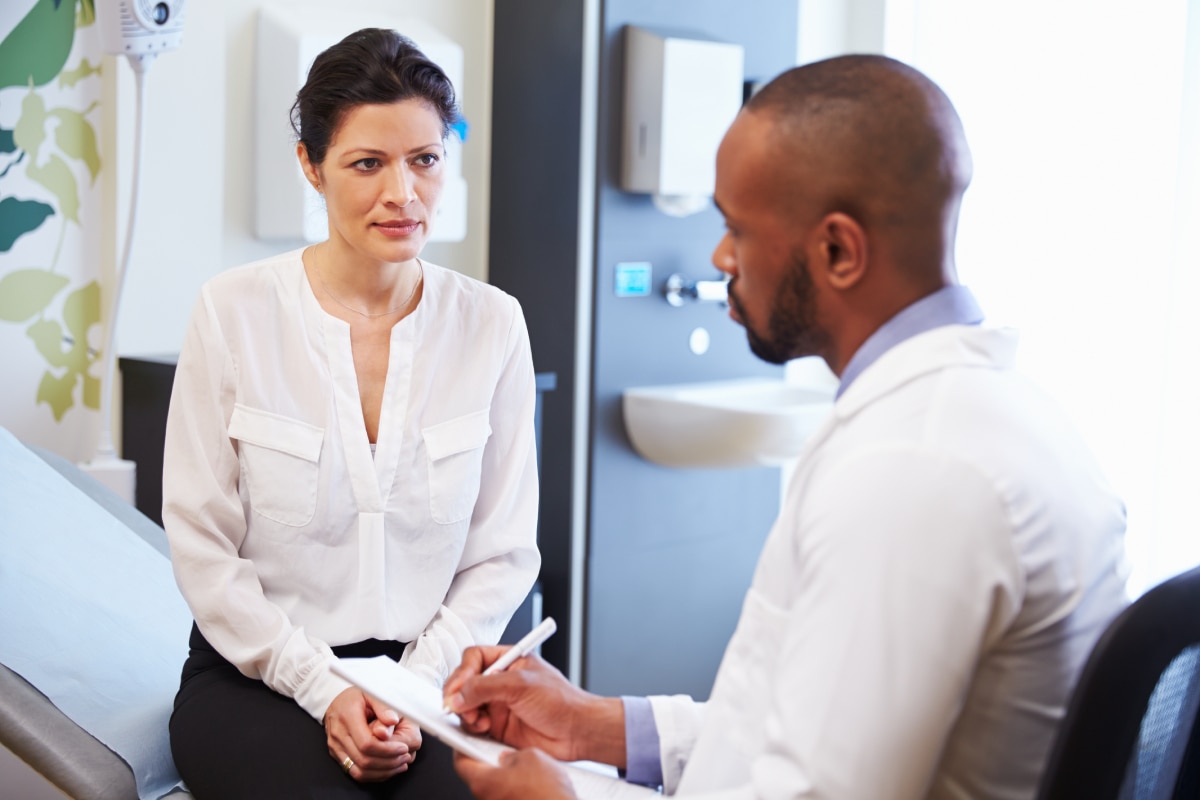 Health care professional talking with a patient in an exam room.