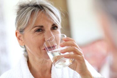 Mujer tomando un vaso con agua.