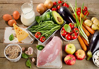 Una variedad de alimentos saludables y nutritivos, incluso verduras, frutas, granos enteros, queso, huevos, leche y pollo.