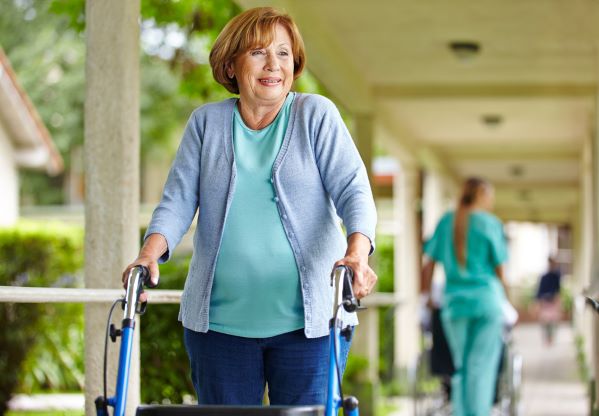 An older woman using a walker.