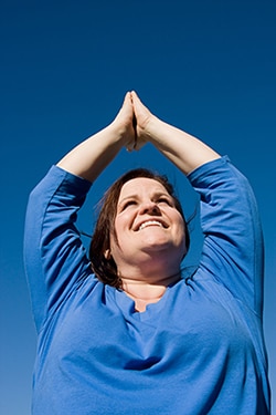 Woman with her arms raised over her head in a yoga pose.