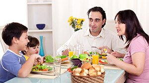 Family sitting at the family table eating a healthy meal.