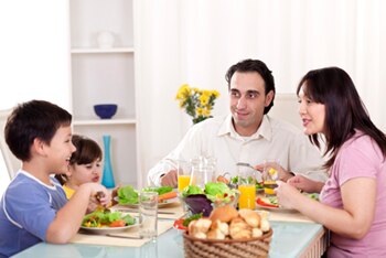 A man, woman, and two children sharing a meal around a dinner table.