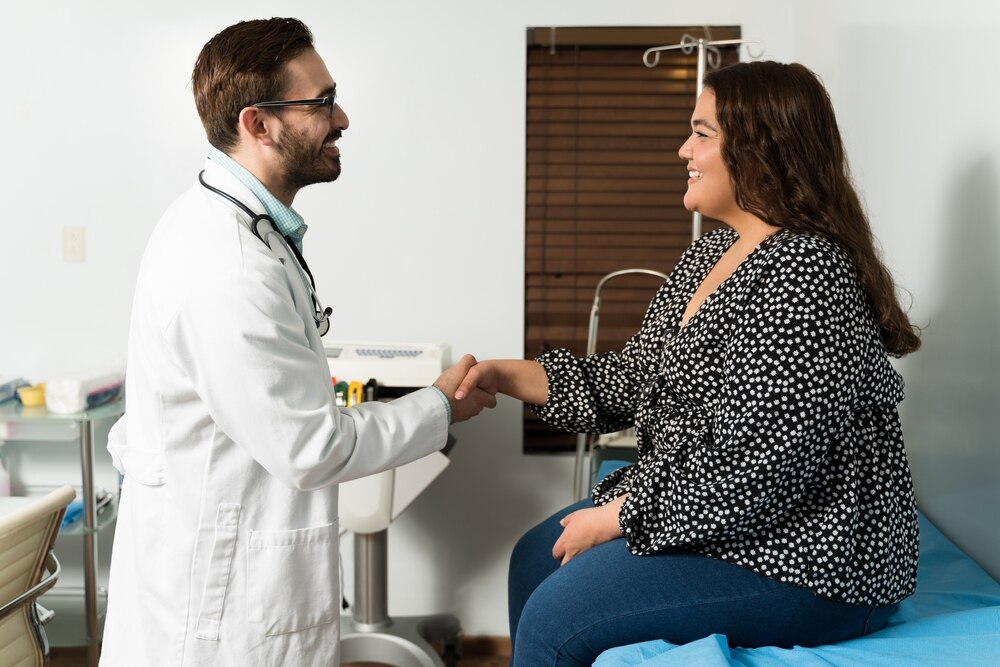 Health care professional shaking hands with a patient who is overweight.