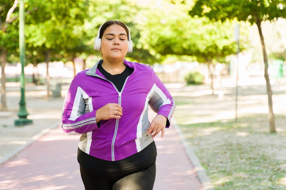 Una mujer joven con auriculares sale a correr por el parque.