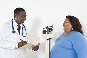 Health care professional talking with woman standing on a scale.