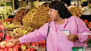 Una mujer escogiendo frutas y verduras en el supermercado.