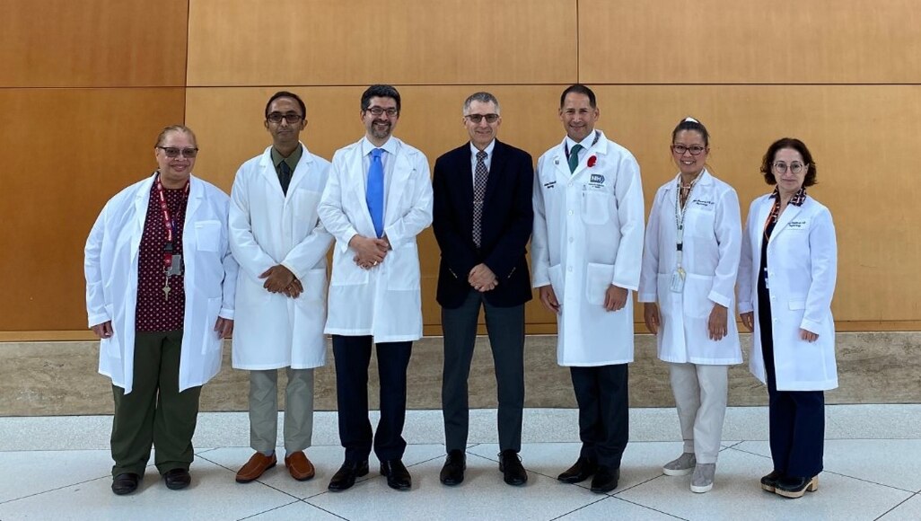 Lab members standing in front of the NIH Clinical Center sign.