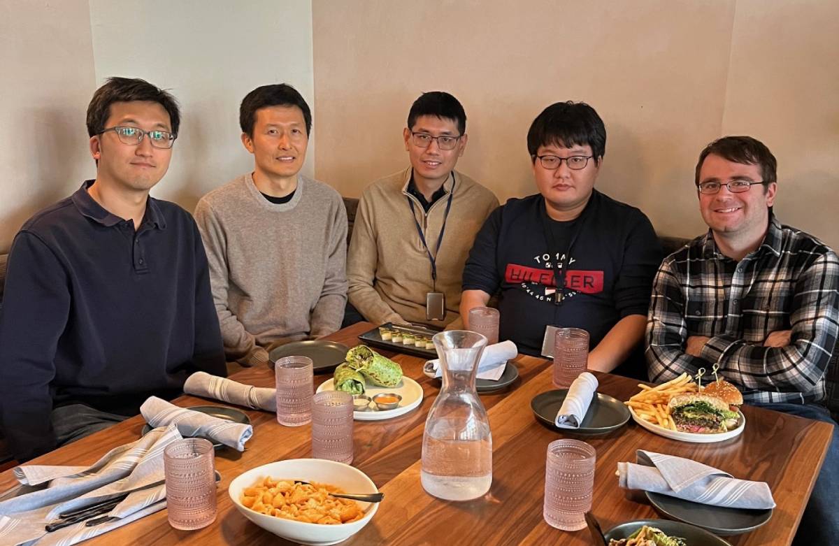 Lab members sitting at a table with food with food in front of them.