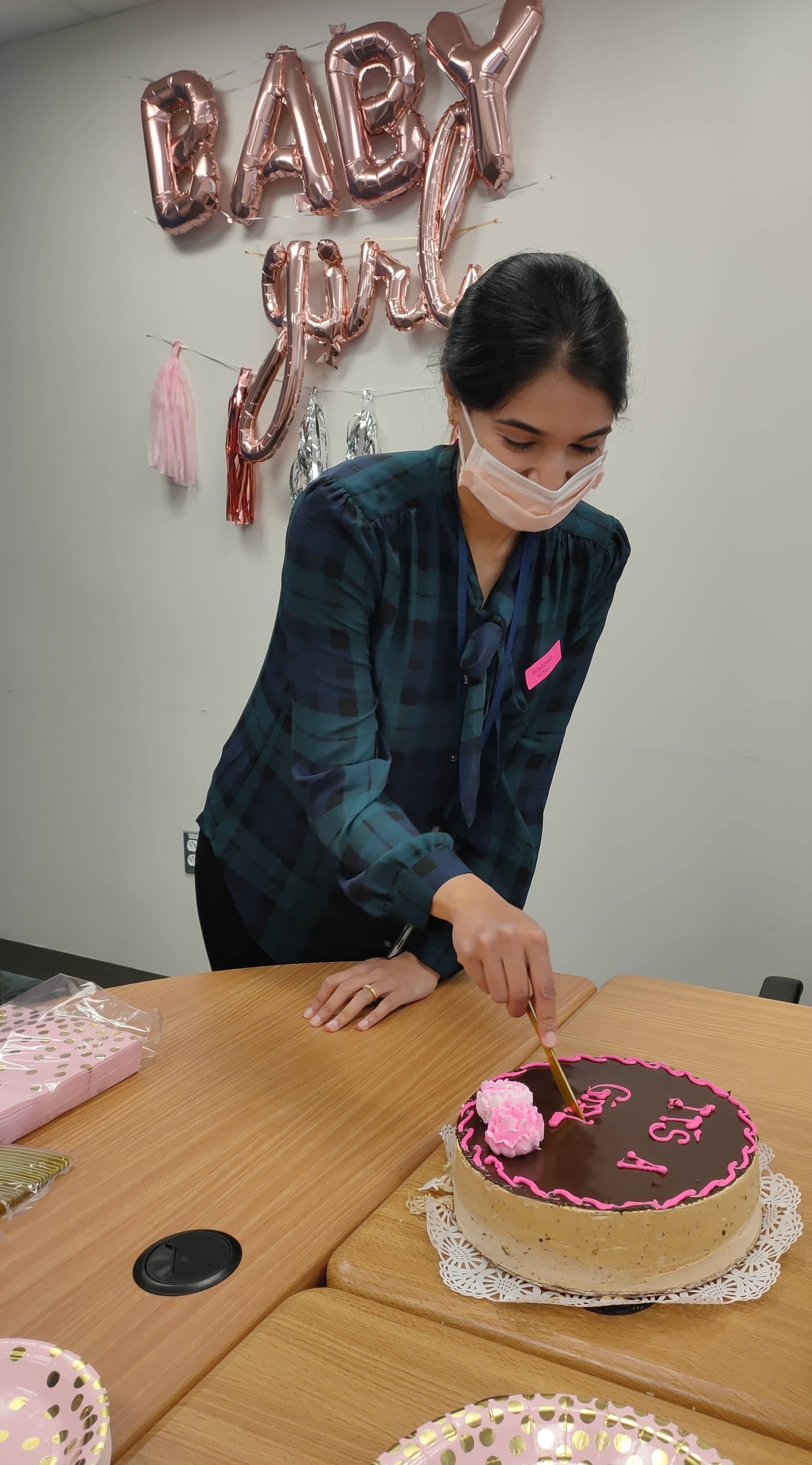 Lab member cutting a cake that reads It's a Girl.