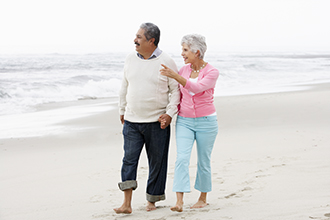 A couple holding hands and walking on the beach.